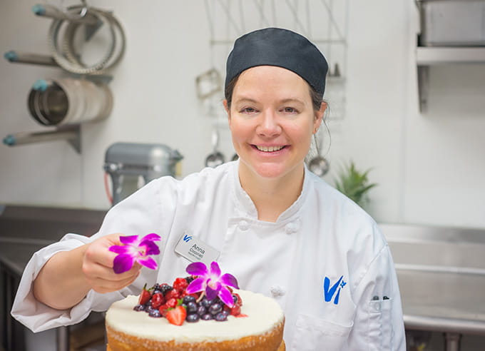 A pastry chef decorates a cake.